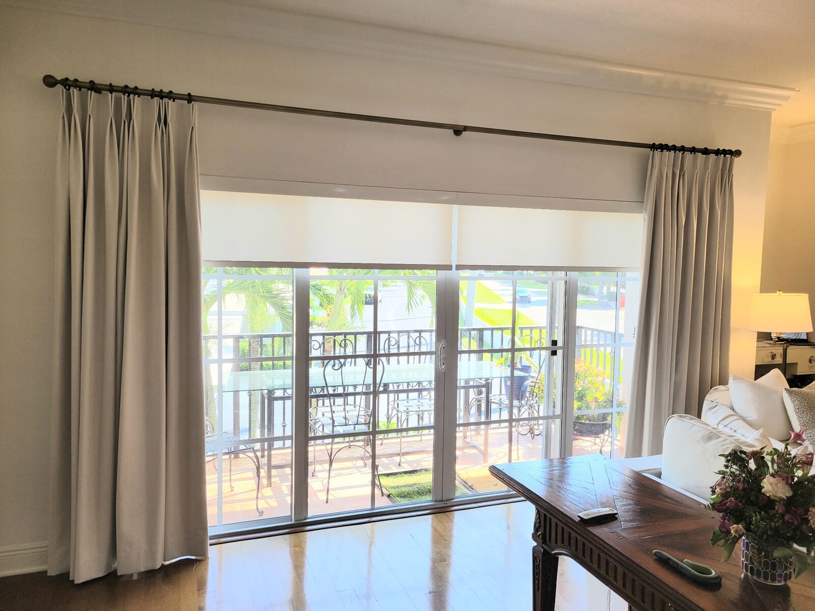Custom stationary drapery panels paired with roller shades over sliding glass doors